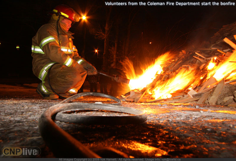 Volunteers from the Coleman Fire Department start the bonfire