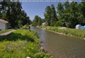 A walking path parallels the Crowsnest River, winding through the residential area of lower Coleman