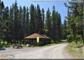 A group firepit and many picnic tables surround the group shelter
