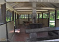 A wood stove and tables inside the group shelter at Racehorse Creek Campground